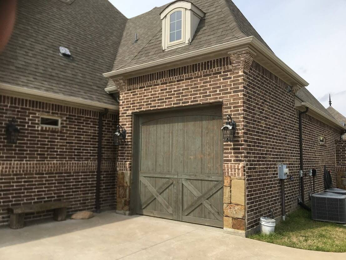 Brick home exterior with a wood garage door and lantern lights
