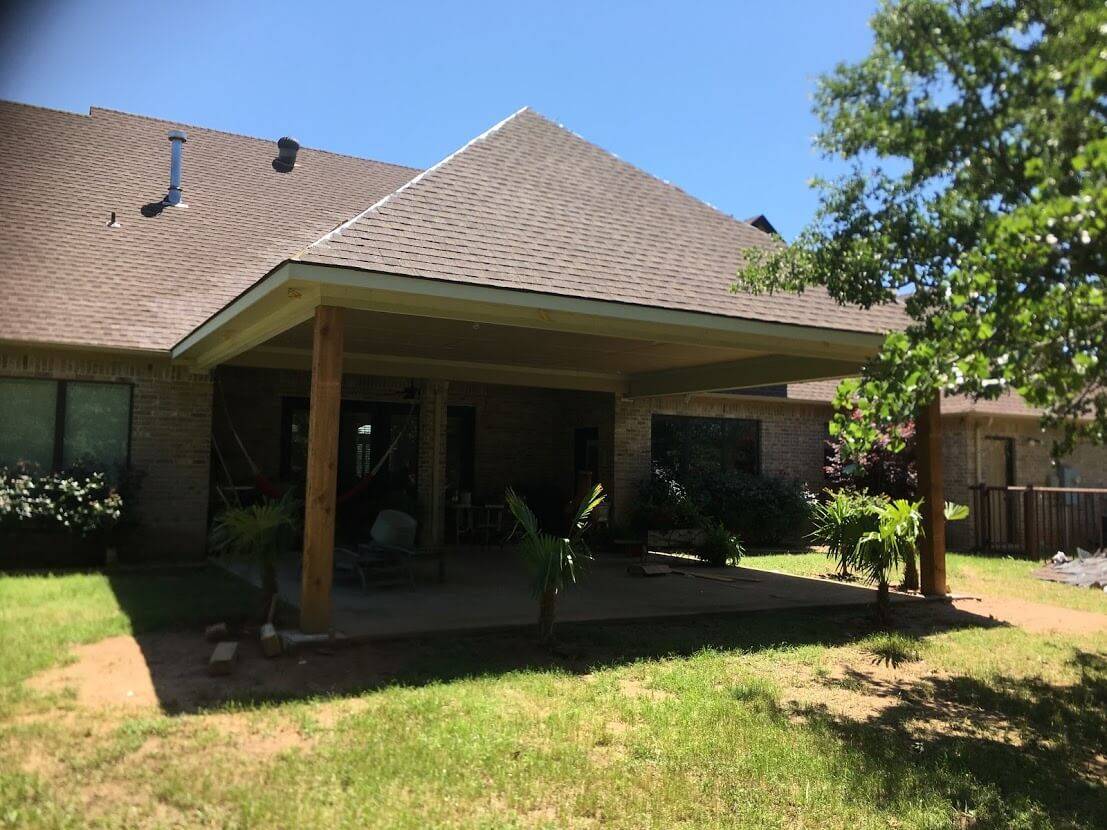 Covered patio with cedar posts and a hip roof at the back of a brick home