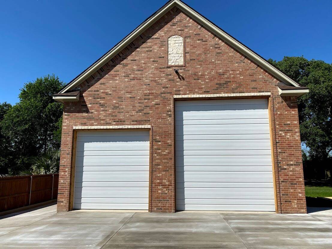 Brick building with two white roll-up garage doors