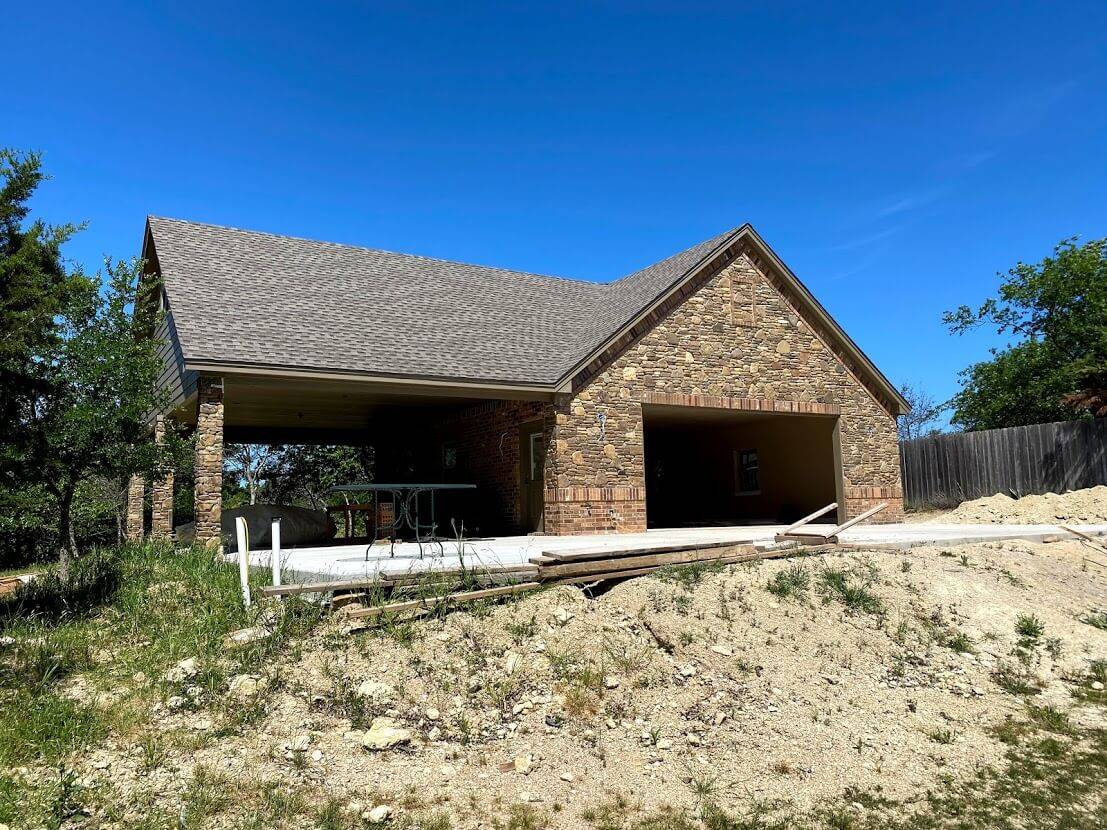 Stone and brick garage with a covered porch, photographed before final site work