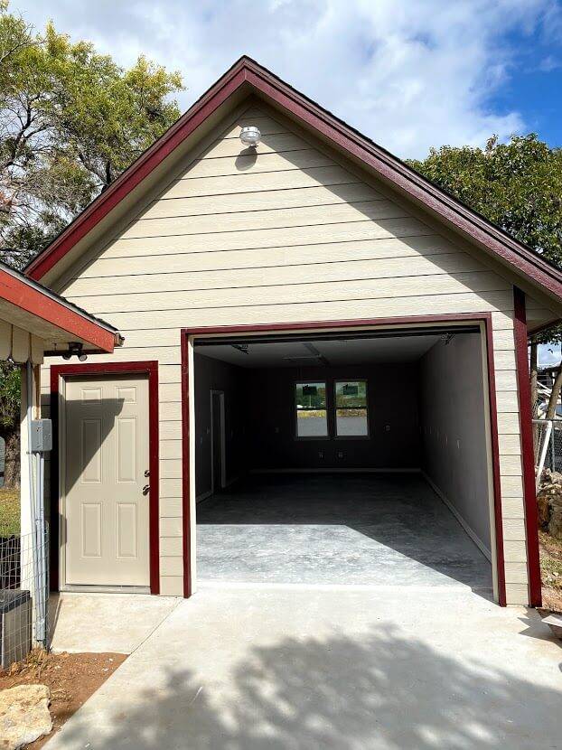 Small garage with red trim, a side door and an open overhead door