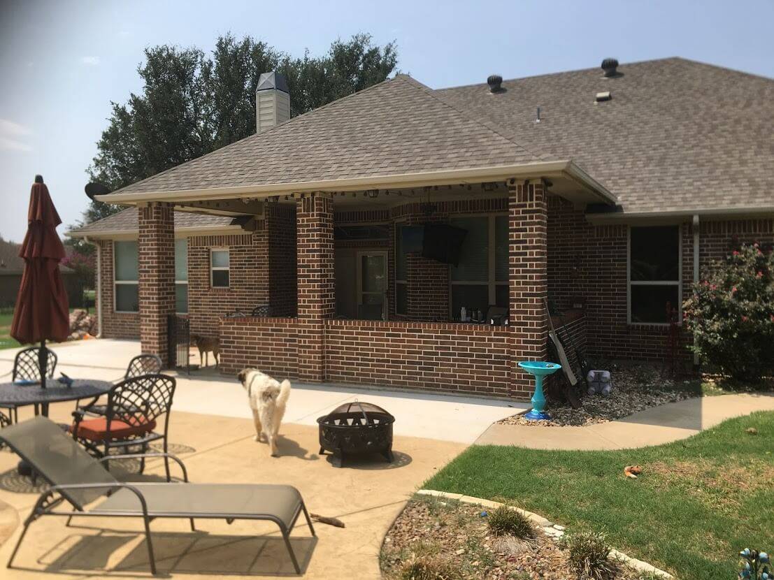 Brick covered patio with a low wall, beside a stamped concrete seating area with a fire pit