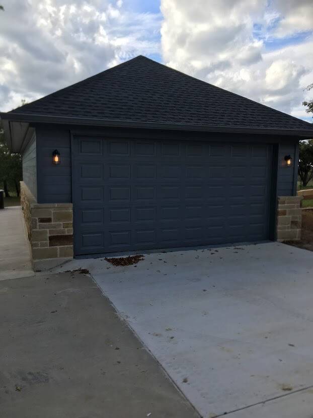 Dark blue garage with a hip roof, lantern lights and stone corners