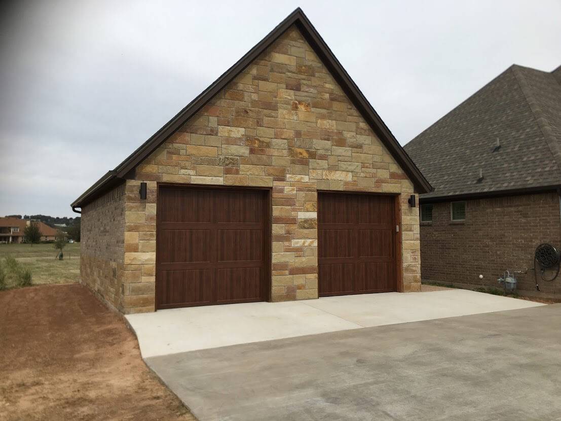 Stone and brick garage with two dark wood-look garage doors