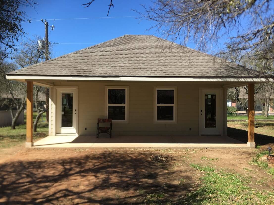Small building with a hip roof, a covered porch with cedar posts and two glass doors